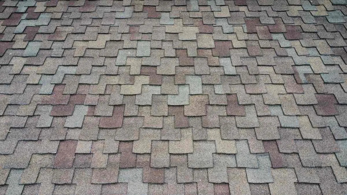 Close view of multitone asphalt shingles with gray, tan, muted red and greenish granules